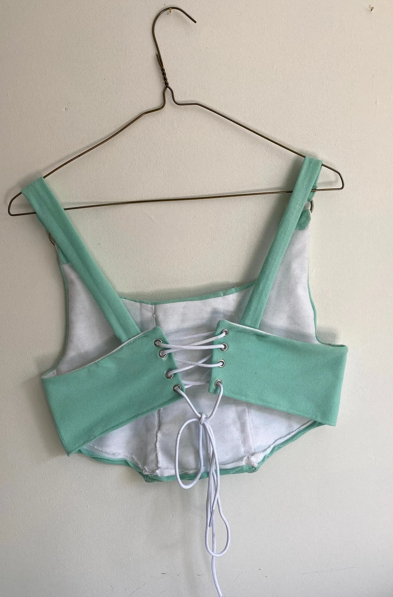 The back of the corset top, with white laces threaded through metal eyelets